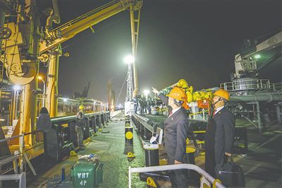 图①:夜晚,涉案船舶上一片繁忙景象。法官在察看船舶卸载作业情况。