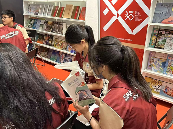 马来西亚读者在中国联合展台翻阅中国书籍。 中国图书进出口(集团)有限公司供图