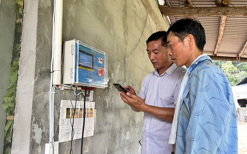 技术员指导烟农在手机查看烟叶烘烤状态。杨威摄